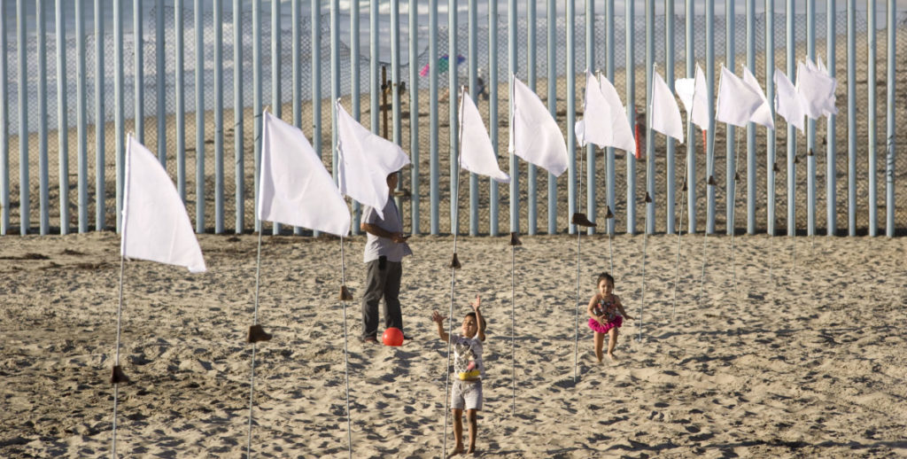 Instalación con banderas blancas en muro EEUU-México tributa a inmigrantes