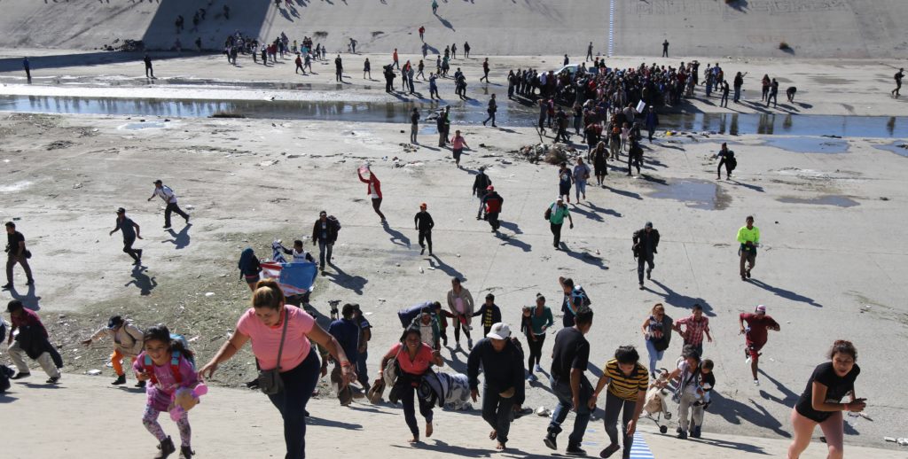 Migrantes intentan cruzar muro con EE.UU. y reciben gas lacrimógeno