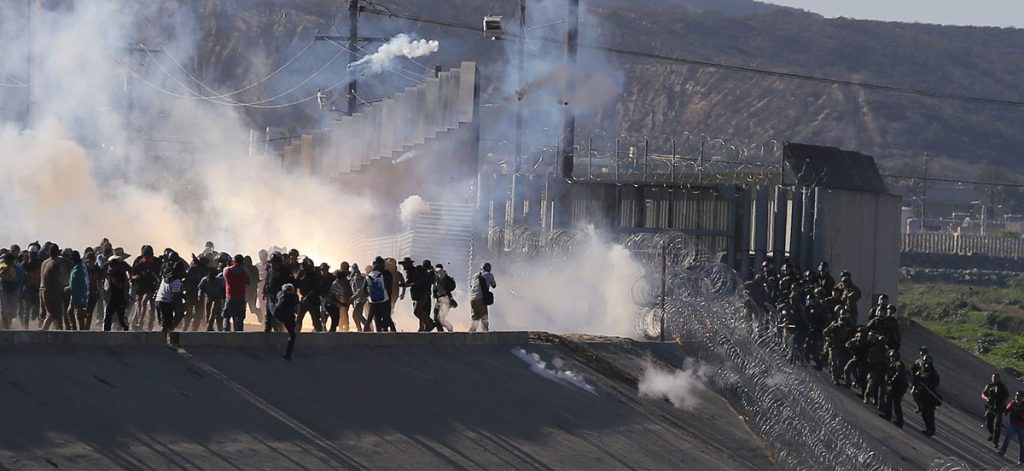 Migrantes intentan cruzar muro con EE.UU. y reciben gas lacrimógeno