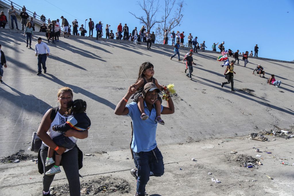 Migrantes intentan cruzar muro con EE.UU. y reciben gas lacrimógeno