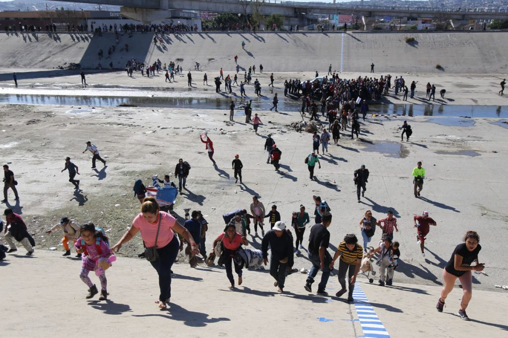 Migrantes intentan cruzar muro con EE.UU. y reciben gas lacrimógeno